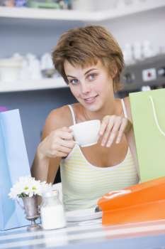 Young woman sitting at a table taking a break from shopping and drinking tea