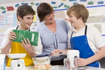 Students preparing ingredients in cooking class with teacher