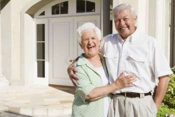 Senior couple standing outside their home