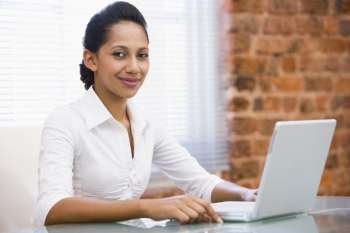 Businesswoman in office with laptop smiling
