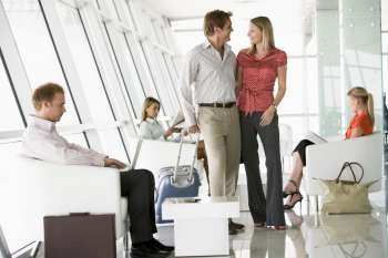 Couple waiting with other airline passengers in departure gate