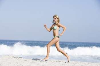Woman in a two piece bathing suit running on a beach