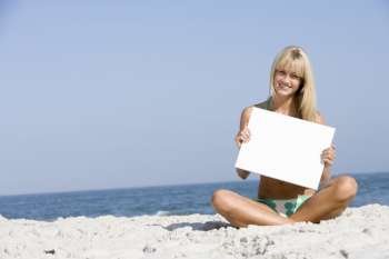 Woman holding a blank card on a beach