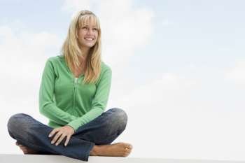 Blonde woman in a green sweater sitting outdoors