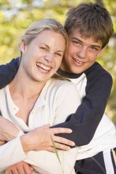 Woman and young boy embracing outdoors and smiling