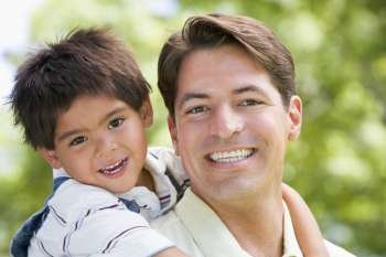 Man and young boy embracing outdoors smiling