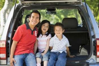 Man with two children sitting in back of van smiling