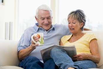 Couple in living room reading newspaper with coffee smiling