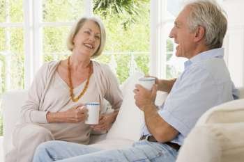 Couple in living room with coffee smiling