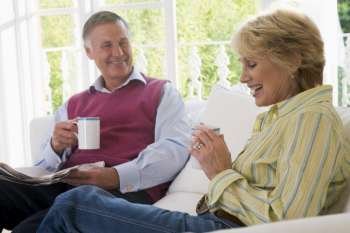 Couple in living room with coffee and newspaper smiling