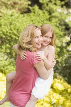 Mother carrying daughter outdoors smiling