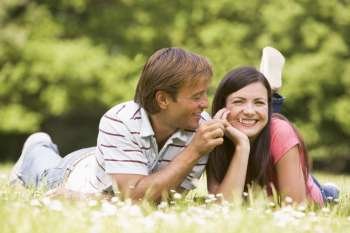 Couple lying outdoors with flower smiling