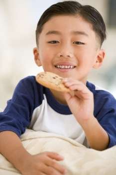 Young boy eating cookie in living room smiling
