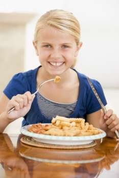 Young girl indoors eating fish and chips smiling