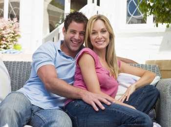 Couple sitting outdoors on patio smiling