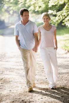 Couple walking outdoors holding hands and smiling