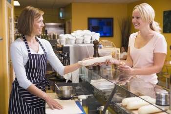 Woman standing at counter in restaurant serving customer and smiling