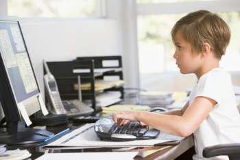 Young boy in home office with computer typing