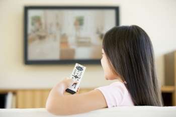 Young girl in living room with flat screen television and remote control