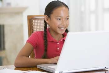 Young girl with laptop in dining room smiling