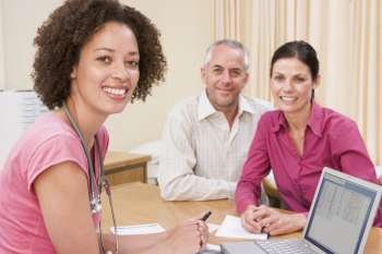 Doctor with laptop and couple in doctor´s office smiling