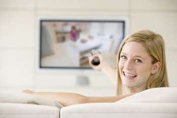 Woman in living room watching television smiling