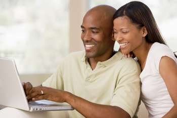Couple in living room using laptop and smiling
