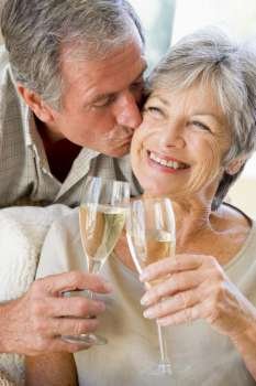 Couple in living room toasting champagne kissing and smiling