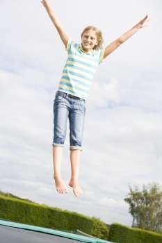 Young girl jumping on trampoline smiling