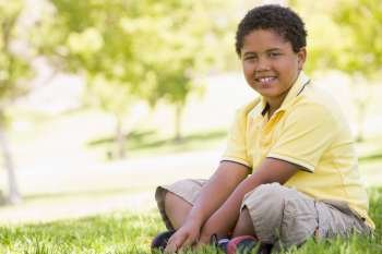 Young boy sitting outdoors smiling