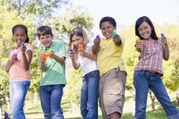 Five young friends with water guns outdoors smiling