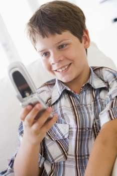 Young Boy Sitting On A Sofa Texting On A Mobile Phone