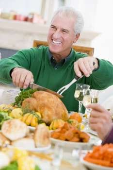 Man Carving Up Turkey At Christmas Dinner