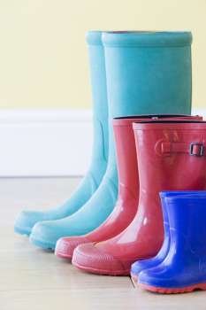 Three Pairs Of Colorful Gumboots In A  Row