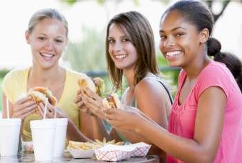 Teenage Girls Sitting Outdoors Eating Fast Food 
