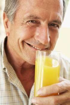 Senior Man Smiling At Camera And Drinking Orange Juice