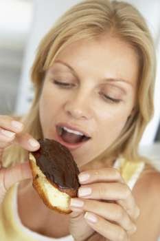 Mid Adult Woman Eating A Chocolate Eclair