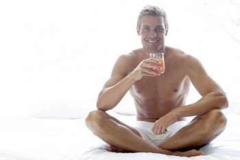 Mid Adult Man Sitting On Bed Drinking