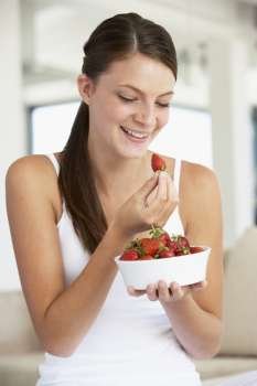 Young Woman Eating A Bowl Of Fresh Strawberries