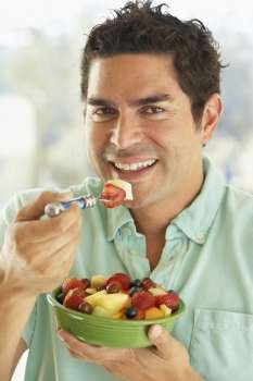 Mid Adult Man Holding A Bowl Of Fresh Fruit Salad Smiling At The Camera