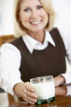 Senior Woman Holding A Glass Of Milk, Smiling At The Camera