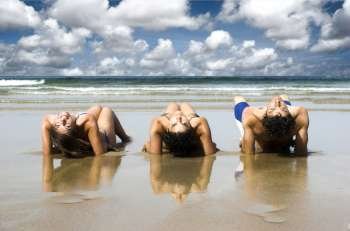Three best friends seated on the sand having fun on the beach