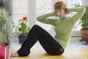 Young woman doing sit-ups on exercise mat at home