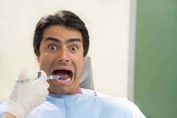 dentist holding a syringe and anesthetizing his patient. Copy space on the right
