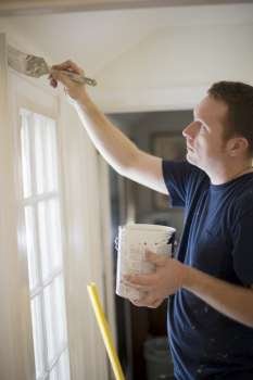 Young man painting door trim inside a house