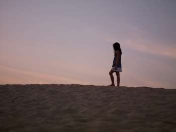 Silhouette of young girl on beach at sunset