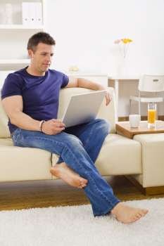 Man browsing internet on laptop computer at home.