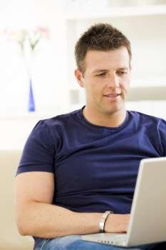 Man sitting on sofa at home and using laptop computer.