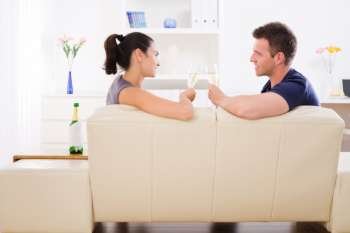 Love couple drinking champagne at home on sofa.