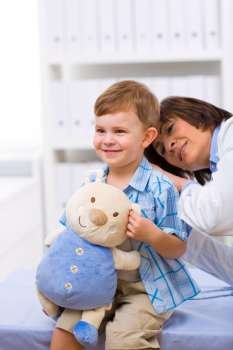Senior female doctor examining happy child, smiling.